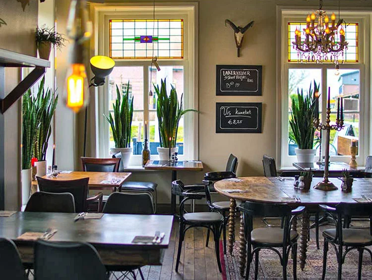 Restaurantzaal met glas-in-loodramen, een kroonluchter en krijtborden aan de muur