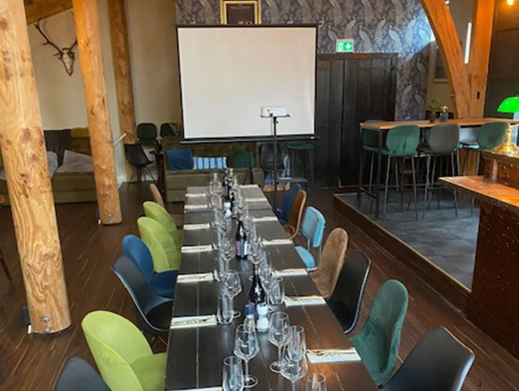 Zaal Yonkers ingericht om te vergaderen, met een lange tafel, wijnglazen en een projectiescherm