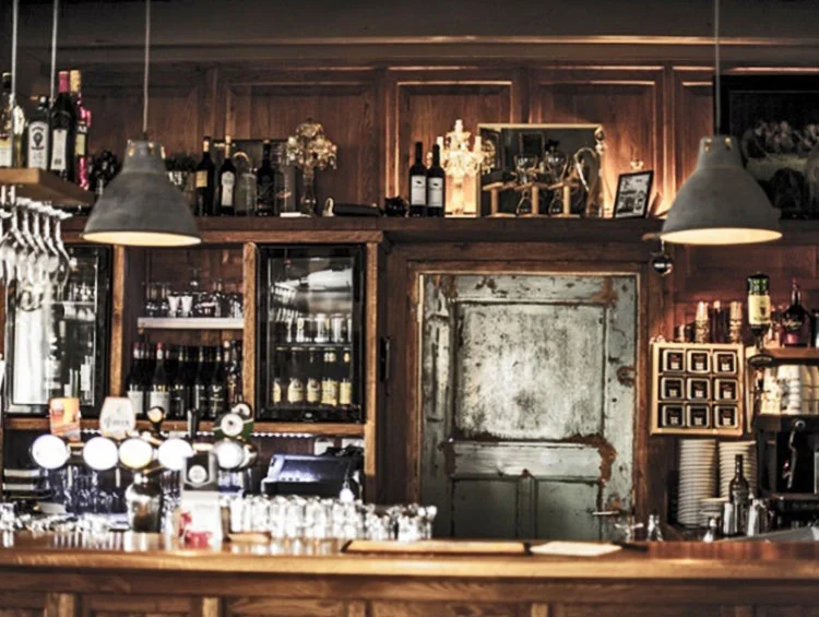 Houten bar met tapkranen, flessen wijn en een oude deur