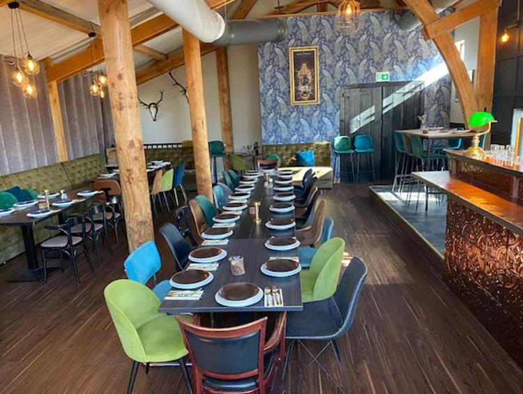 Zaal Yonkers met houten balken in het dak, een lange gedekte tafel en de koperen bar